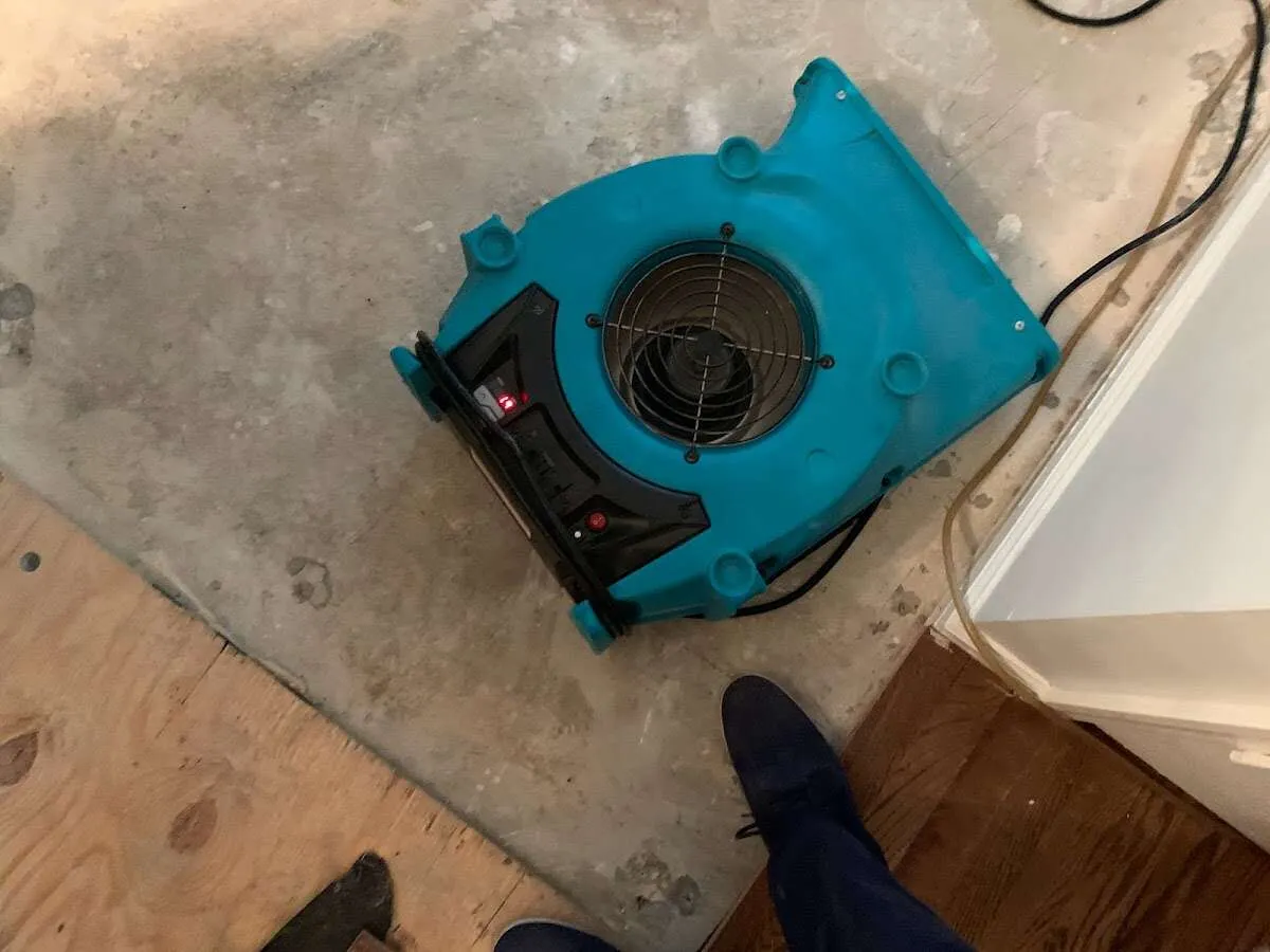 Air mover drying subfloor during Commercial Water Damage Restoration in Salina
